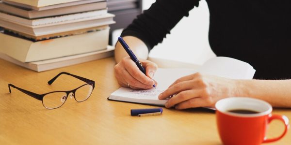 closeup-shot-woman-working-studying-from-home-with-red-coffee-cup-nearby_181624-19822